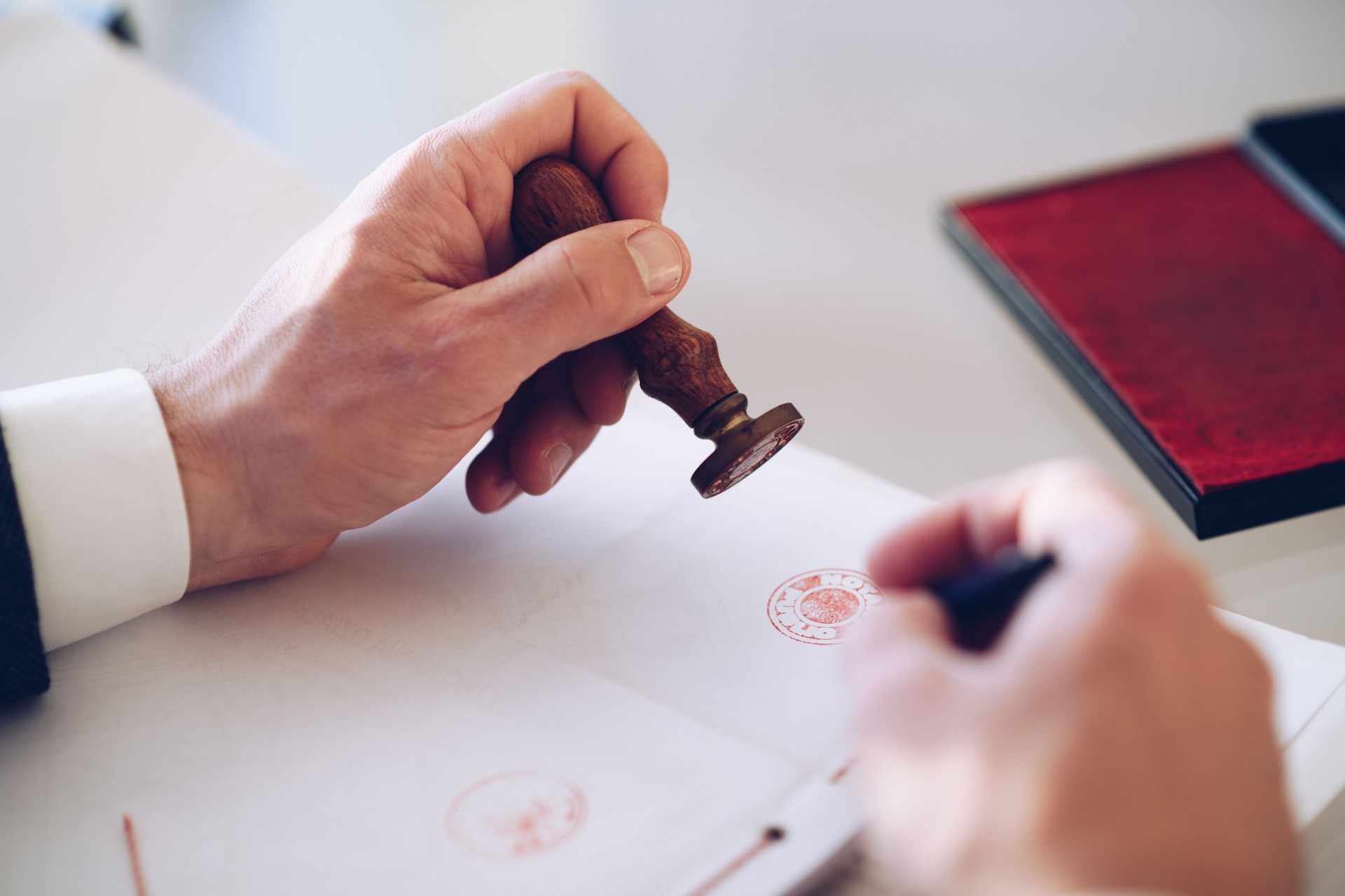 Close-up of a person's hand stamping with approved stamp on certificate or other document.